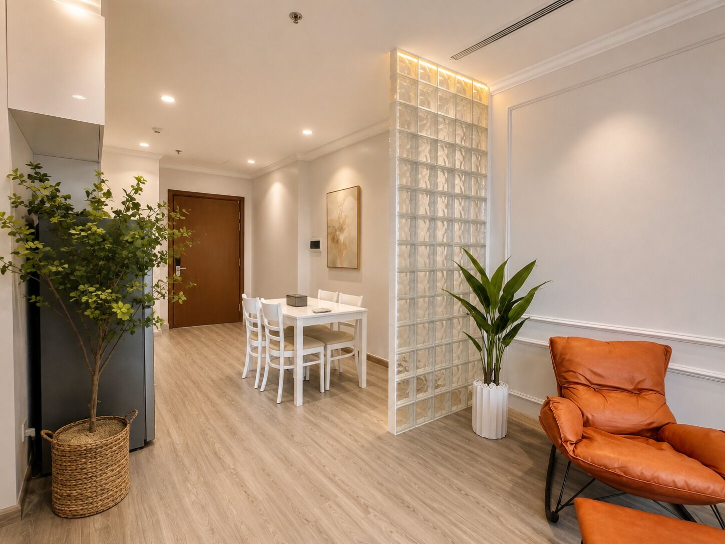 A modern interior with a dining area, a seating area with a leather chair, and a decorative plant.