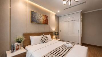 A hotel room with a large bed, a nightstand, a lamp, a painting on the wall, and a wardrobe.