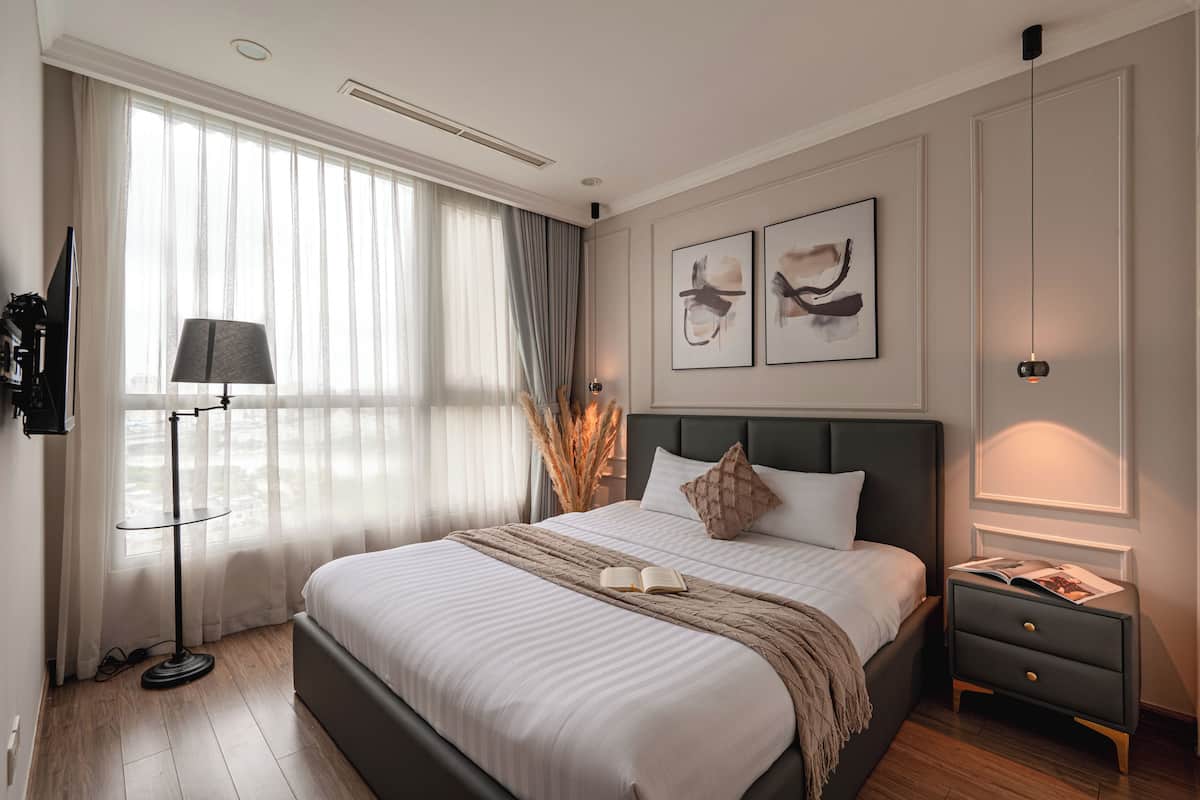 Un dormitorio moderno con una cama grande, mesitas de noche, una lámpara de pie y una obra de arte en la pared.