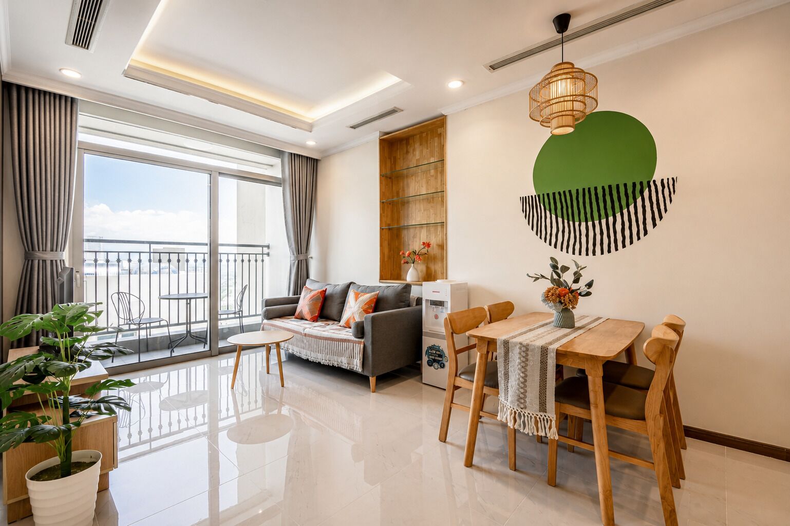 A modern living room with a sofa, dining table, chairs, and a balcony with a view.