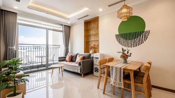 A modern living room with a sofa, dining table, chairs, and a balcony with a view.