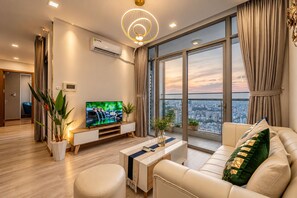 Een moderne woonkamer met een televisie, bank en een stadszicht door grote ramen.
