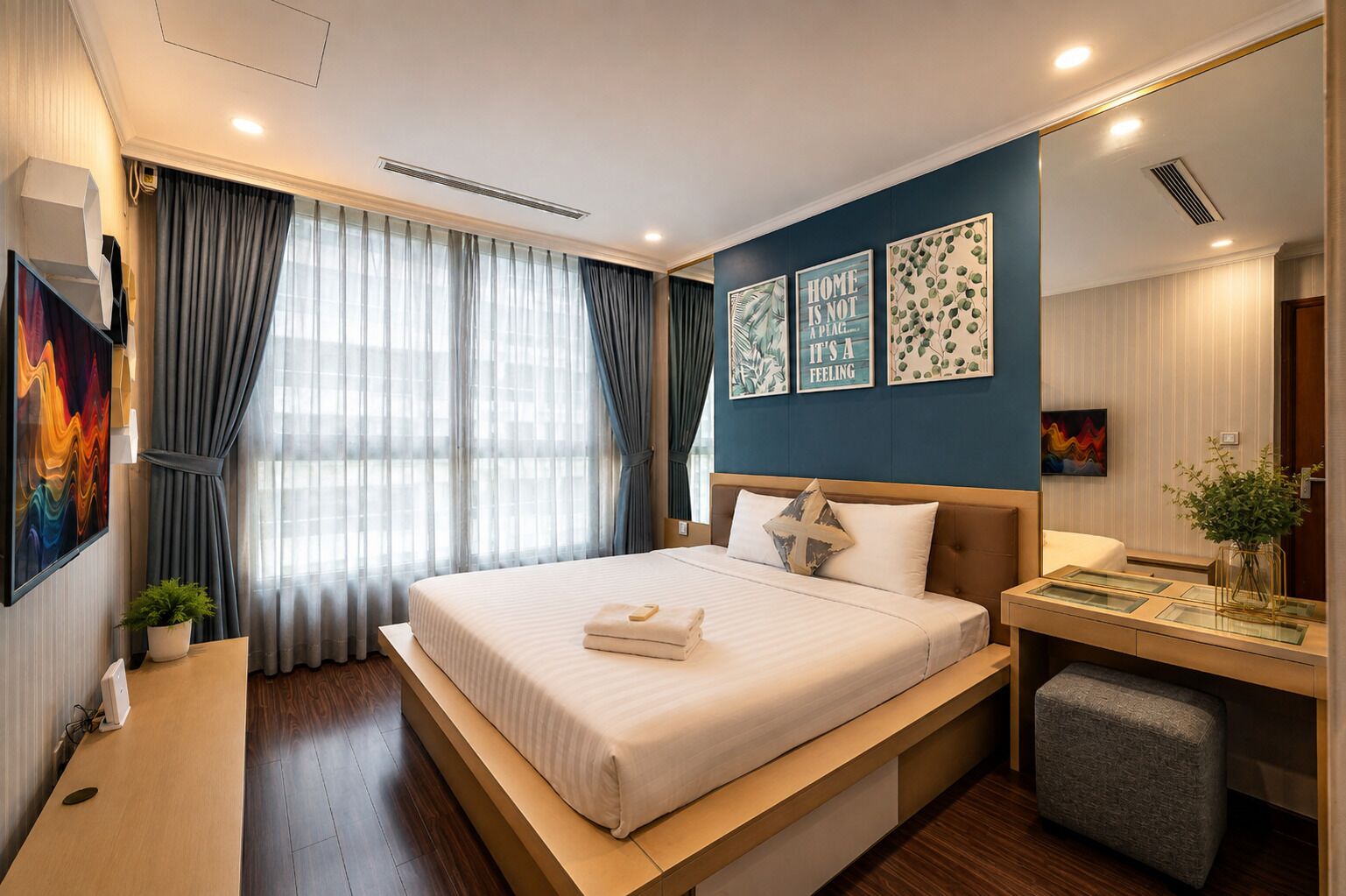 Ein modernes Hotelzimmer mit einem großen Bett, einem Nachttisch, einem Schreibtisch, einem Sessel und einem großen Fenster mit Vorhängen.