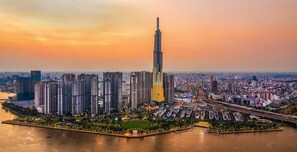 A high-rise building with a unique facade, surrounded by a dense urban area with various other buildings and a river in the foreground. - Vinhomes Skyline Apartment Saigon (Thanh pho Ho Chi Minh)