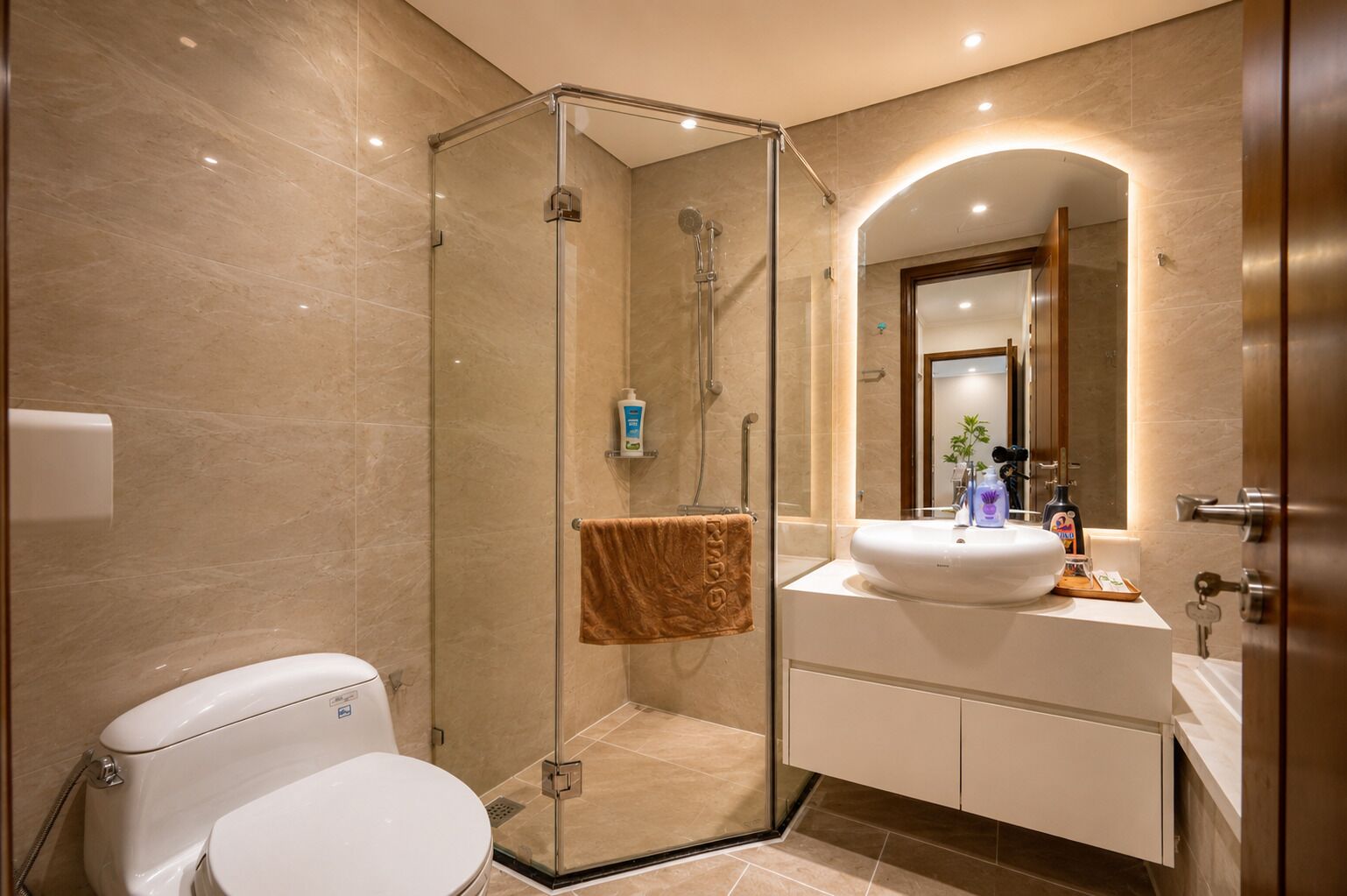 A modern bathroom with a glass-enclosed shower, a white toilet, and a vanity with a mirror.