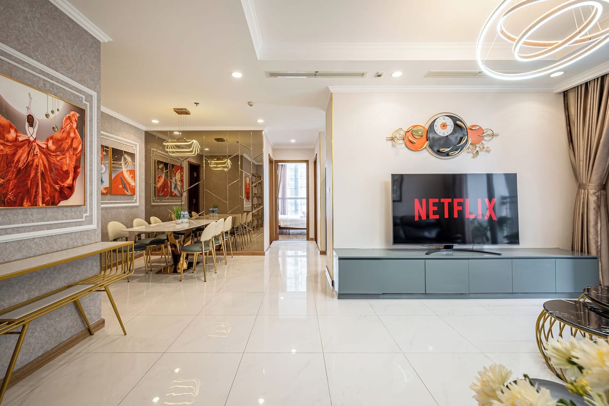 Una sala moderna con televisor de pantalla plana, una zona de comedor con mesa y sillas, y un banco.