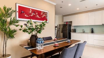 A dining area with a table, chairs, a vase with flowers, and a kitchen in the background.