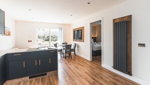 Una cocina moderna con armarios oscuros y un comedor con piso de madera.