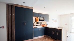 Una cocina moderna con armarios oscuros, suelo de madera y una isla grande con pileta y encimera.
