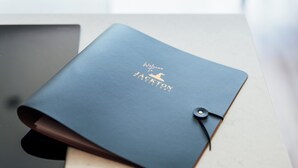Un cuaderno de cuero azul oscuro con el texto "Welcome to JACKTON DISTILLERY" y un pequeño logo de sombrero de bruja.
