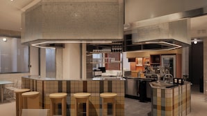 Una cocina moderna con una isla central, taburetes de bar y un techo alto con diseño texturizado.