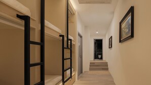 Un pasillo con literas, una escalera y cuadros en la pared.