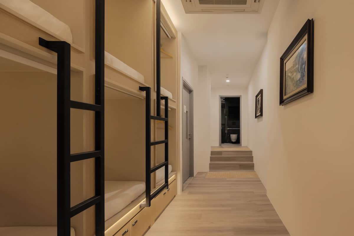 Un pasillo con literas, una escalera y cuadros en la pared.