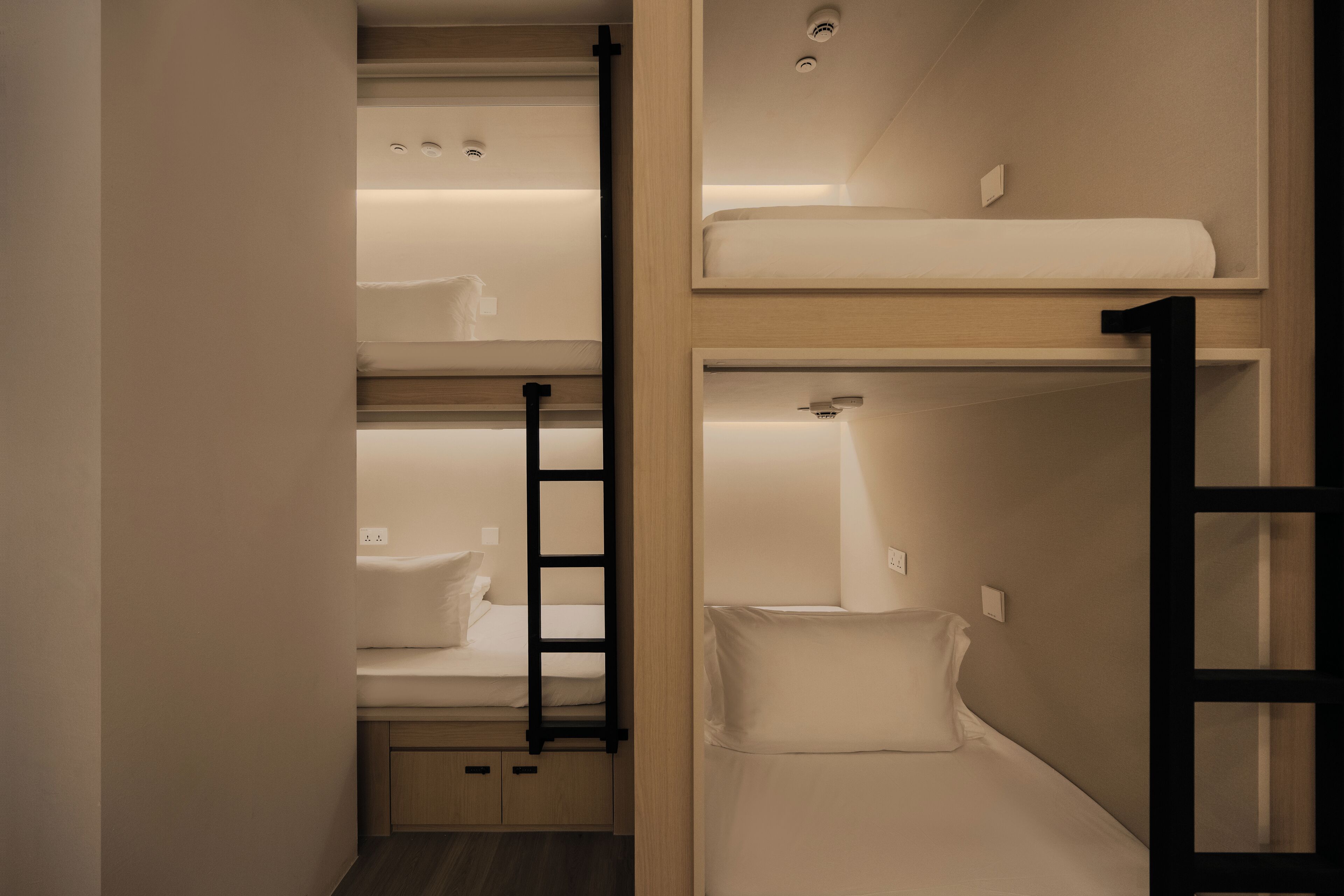 A bunk bed room with a ladder, a small desk, and a shelf.