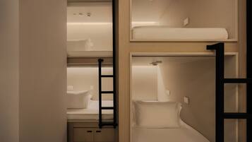 A bunk bed room with a ladder, a small desk, and a shelf.