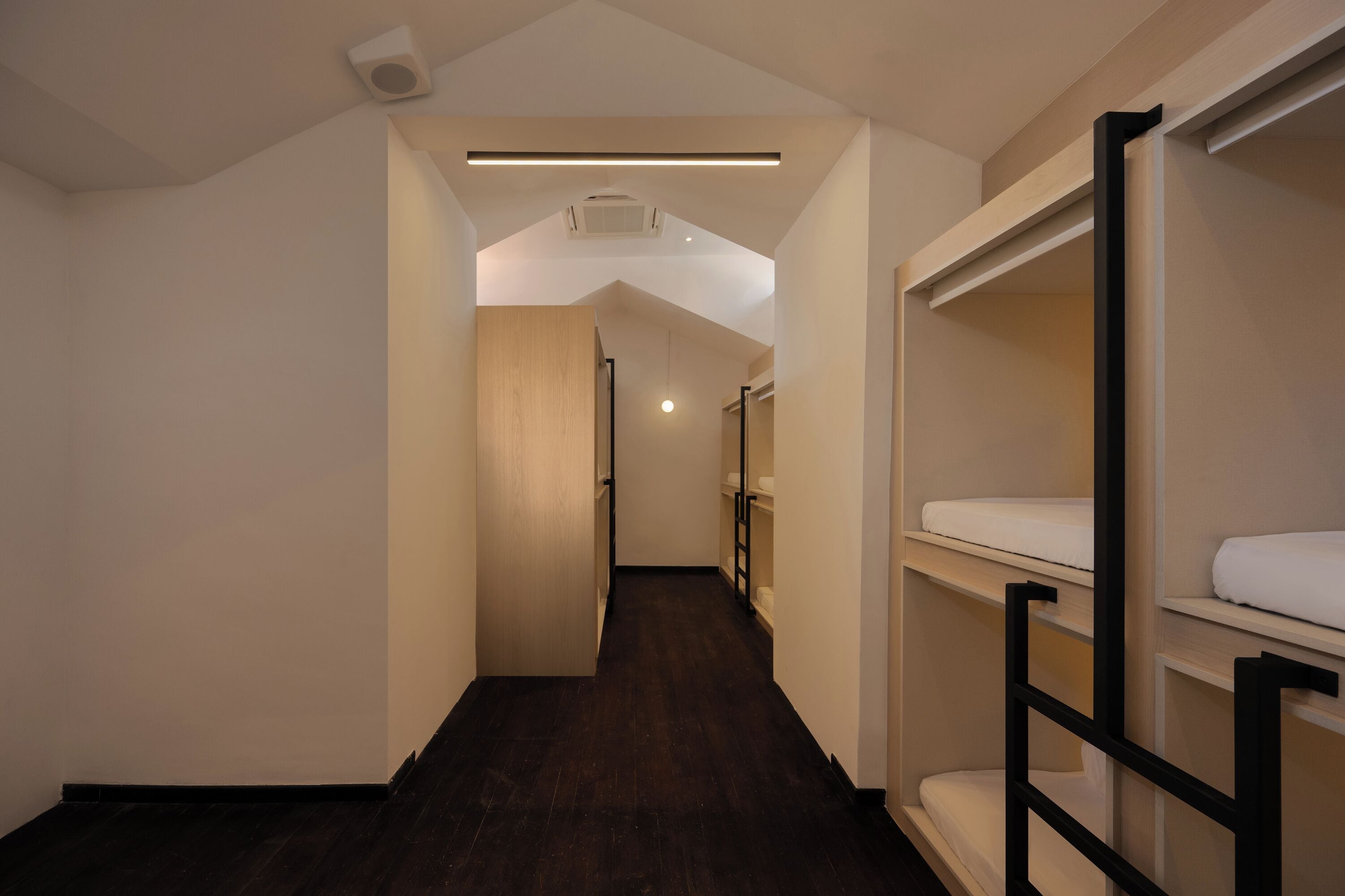 A narrow hallway with bunk beds on one side and a wooden door at the end.