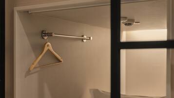 A room with a wooden hanger on the wall, a metal rod, and a ceiling-mounted light fixture.