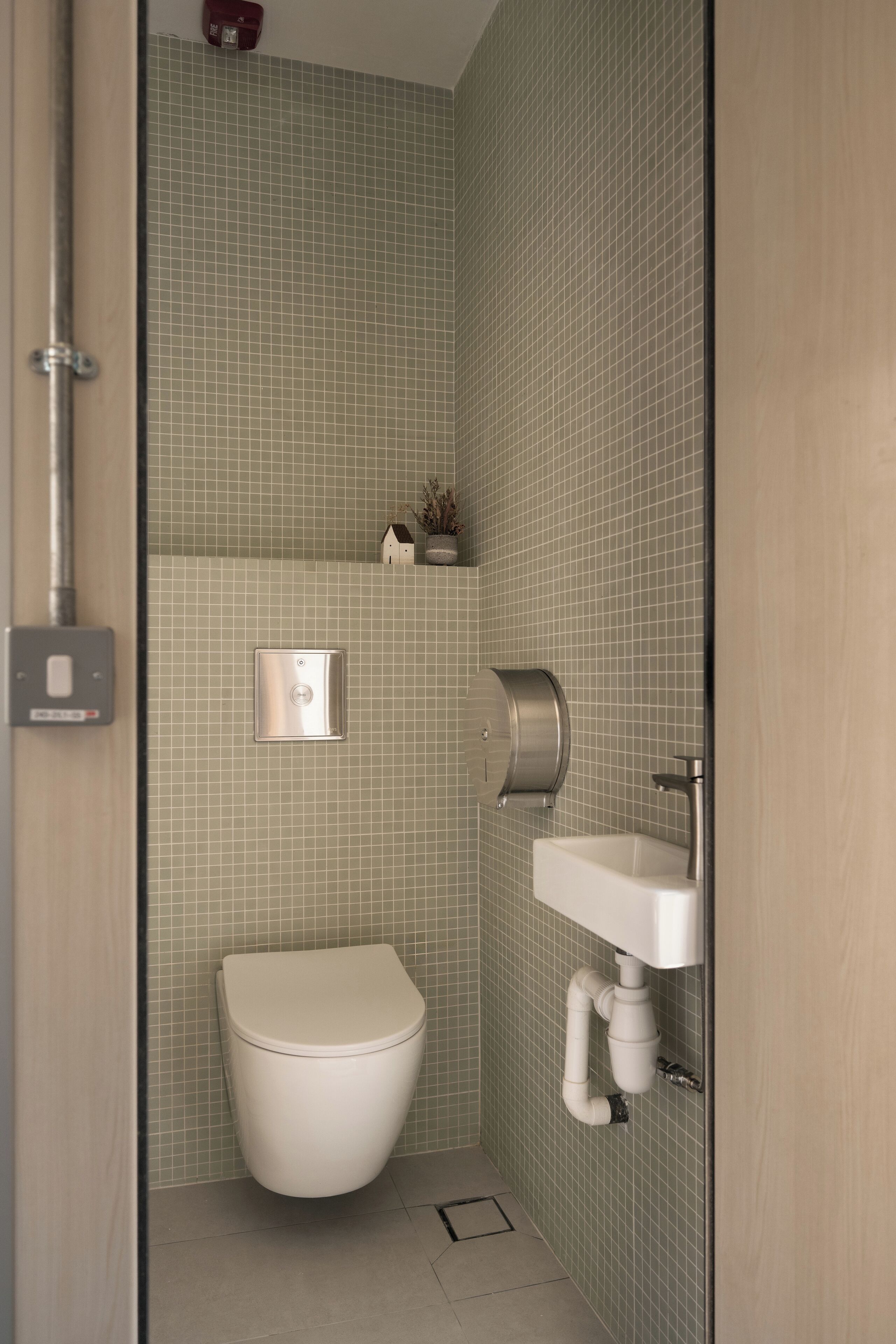 A small, modern bathroom with a toilet, sink, and a shower area.