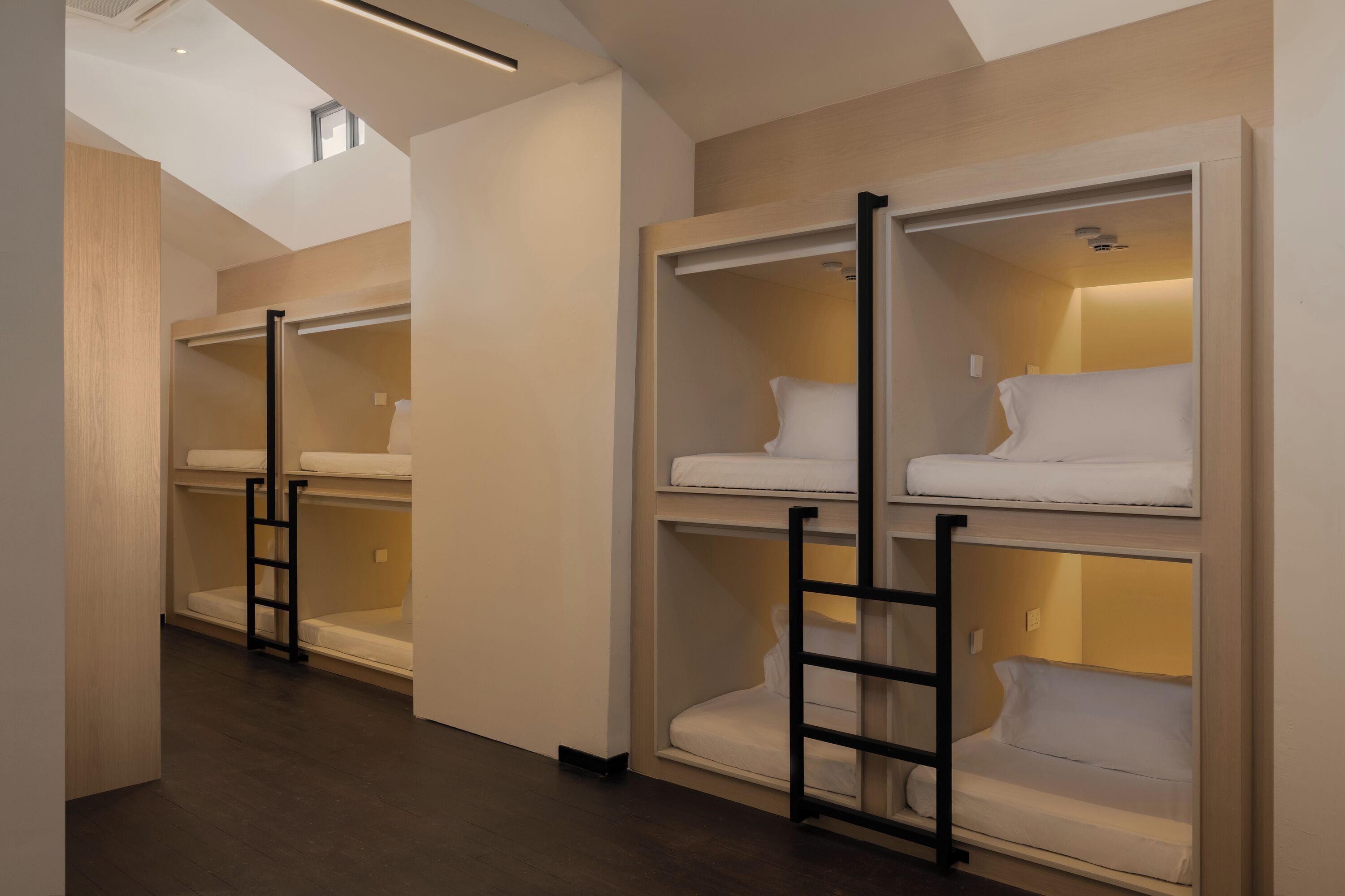A hotel room with bunk beds, a ladder, and a skylight.