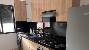 A modern kitchen with wooden cabinets, a stainless steel stove, a built-in oven, and a washing machine.
