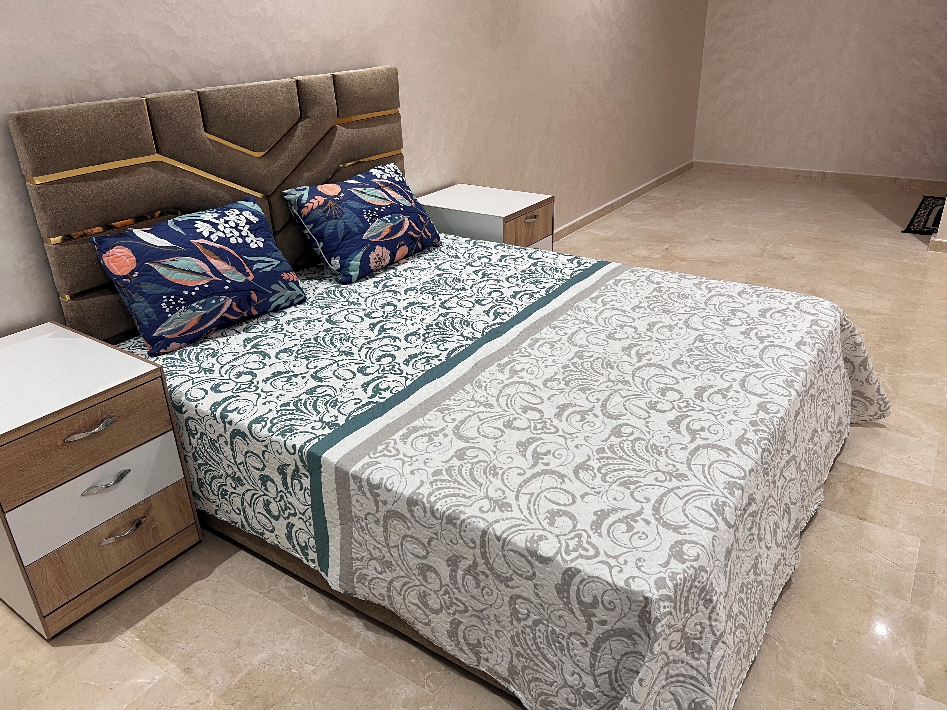 A bedroom with a bed, nightstands, and a wooden drawer unit.