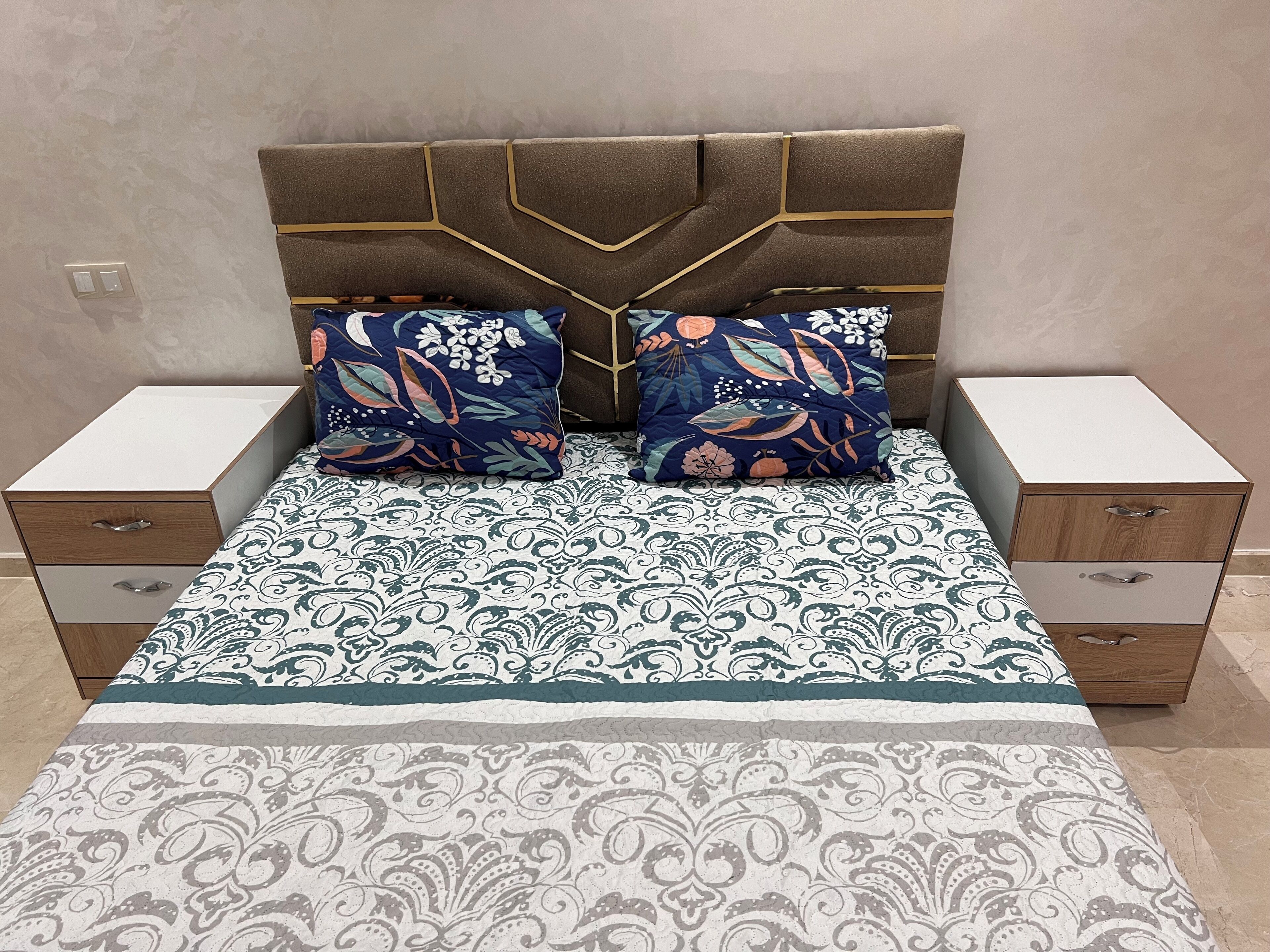 Une chambre à coucher avec un lit, deux tables de chevet et une couvre-lit à motifs.