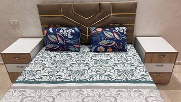 Une chambre à coucher avec un lit, deux tables de chevet et une couvre-lit à motifs.
