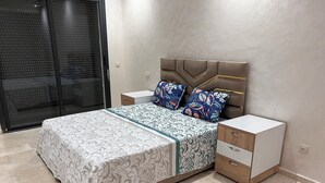 A bedroom with a bed, nightstands, a dresser, and a sliding glass door.