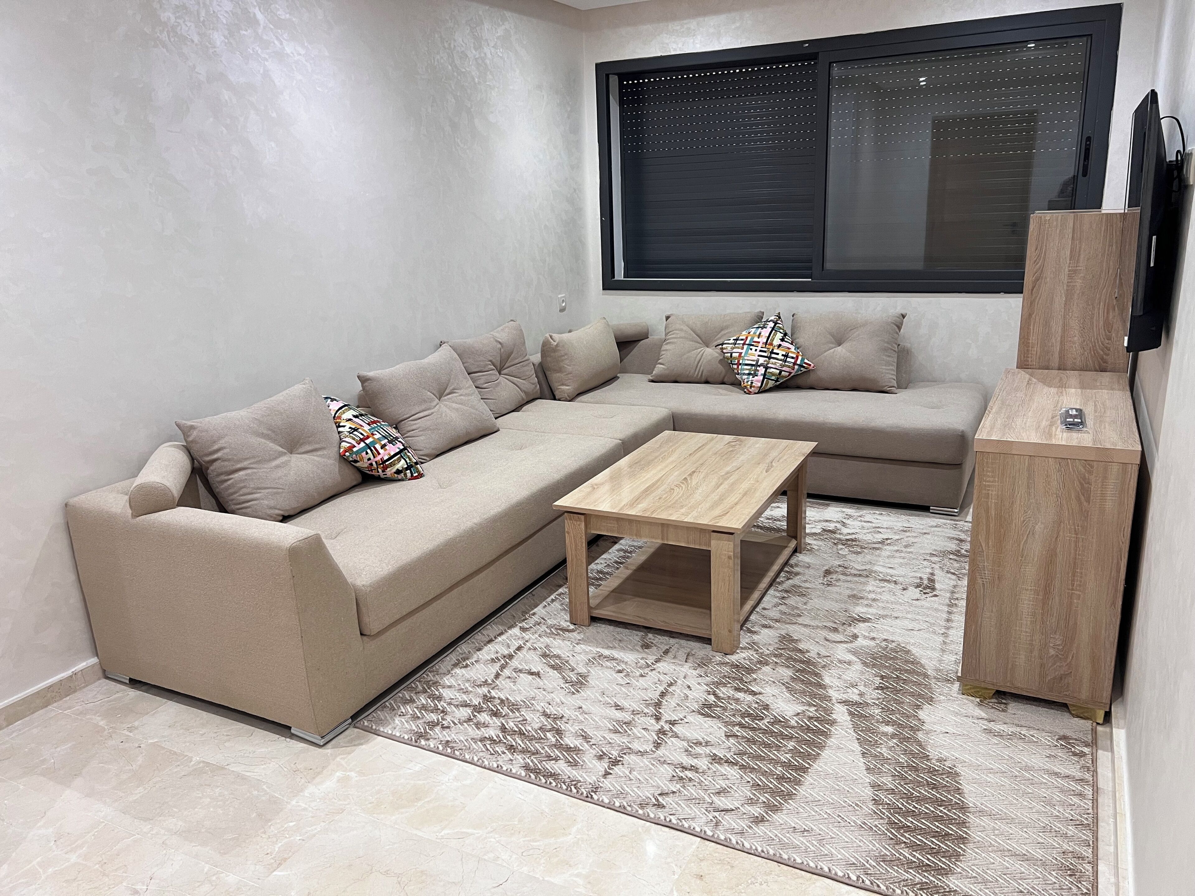 A modern living room with a sectional sofa, a wooden coffee table, and a patterned rug.