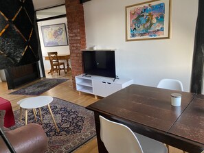 Un salon avec un téléviseur, une cheminée, une table à manger et un tapis.
