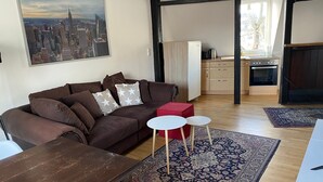 A living room with a brown sofa, a red ottoman, a white coffee table, and a patterned rug. - Stay in a Historic Half-Timbered House (Nürnberg)