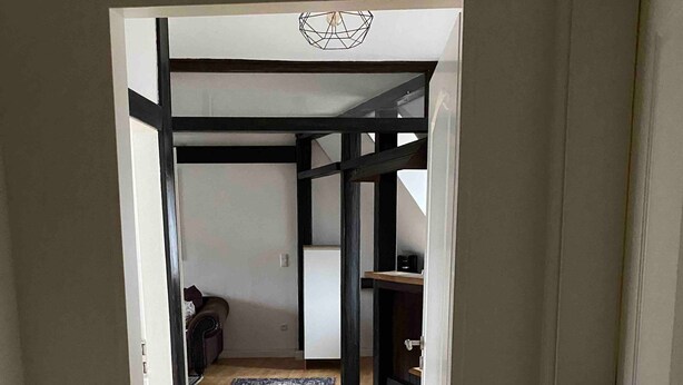 A hallway leading to a room with a wooden floor, a rug, and a fireplace. - Stay in a Historic Half-Timbered House (Nürnberg)