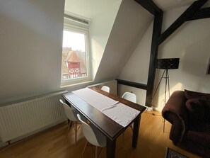Une pièce comprenant une table, des chaises, un radiateur, une fenêtre donnant sur un paysage agréable et un lampadaire.