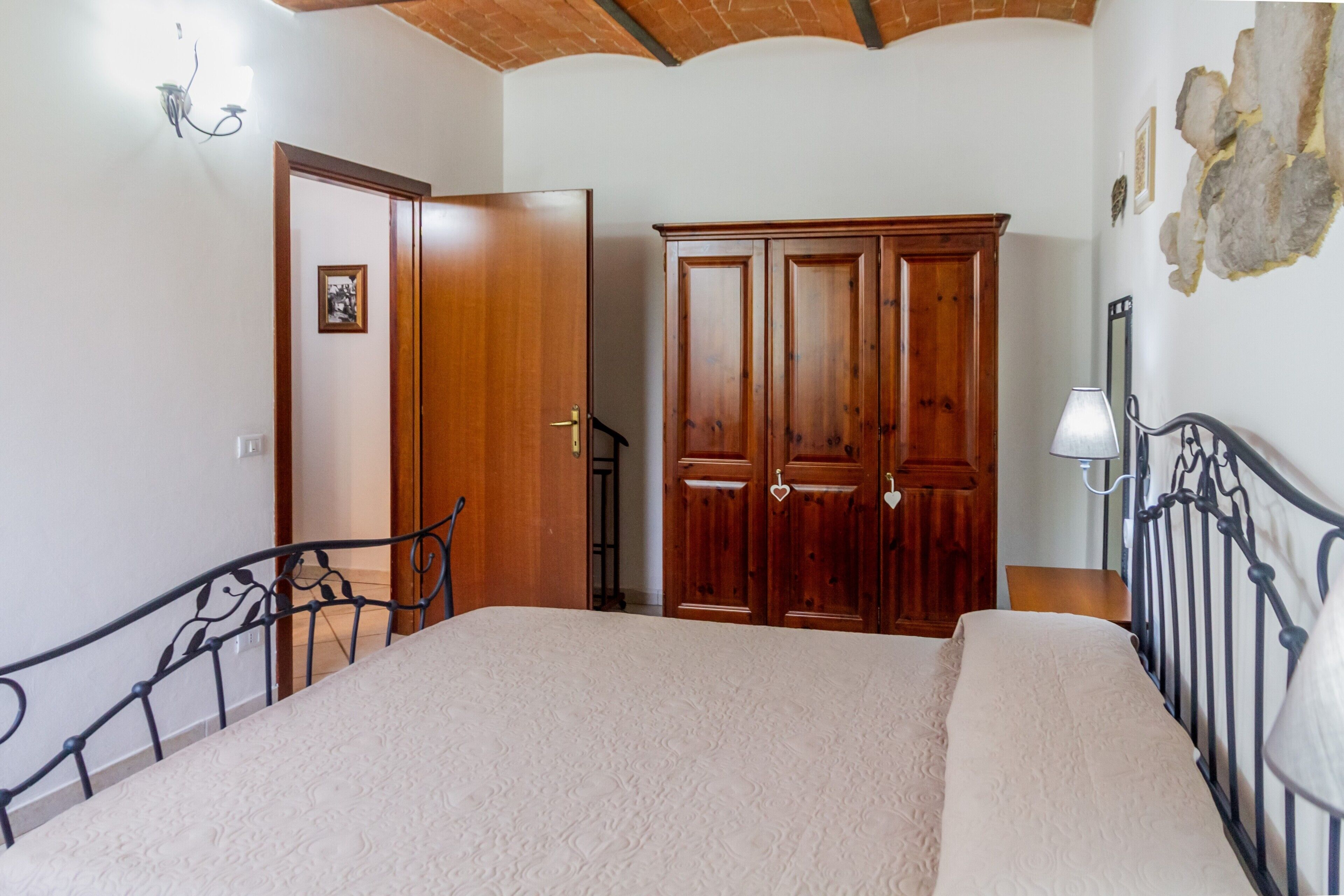 Une chambre à coucher comprenant un lit, une armoire, un escalier et une lampe fixée au mur.
