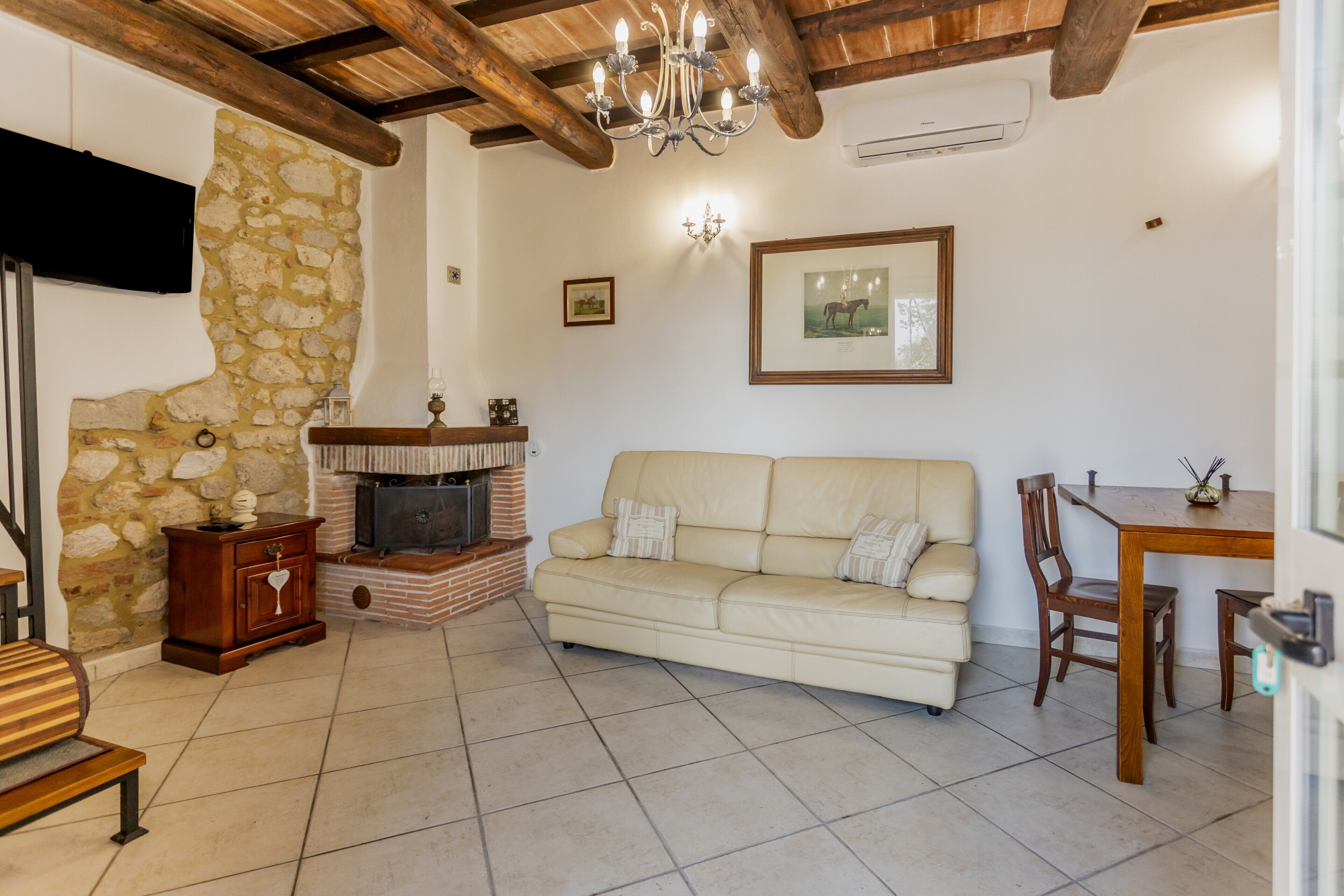 Un salon chaleureux avec un mur en pierre, une cheminée, un canapé, un banc en bois et une table à manger.