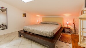 Un dormitorio con cama, lámparas de noche, una decoración con forma de corazón en la pared y un tragaluz.