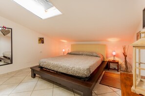 Una camera da letto con un letto, lampade sui comodini, una decorazione a forma di cuore appesa al muro e un lucernario.