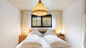 Ein Schlafzimmer mit Bett, Fenster und einer Pendelleuchte.