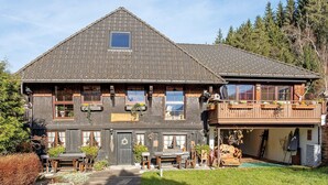 Ein zweistöckiges Gebäude mit einem geneigten Dach, zahlreichen Fenstern und einem Balkon.