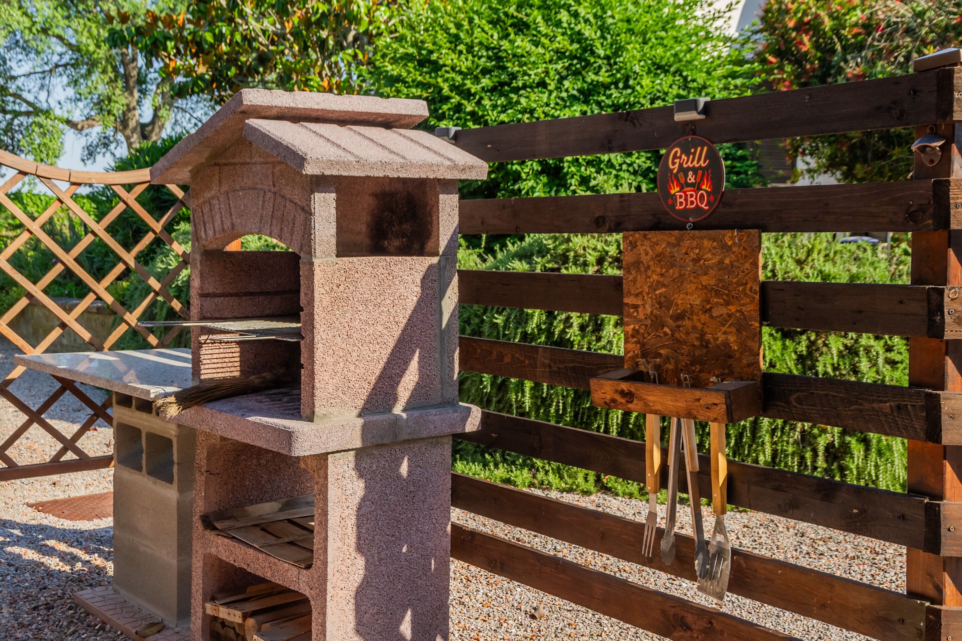 Zona de parrilla exterior con un cartel que indica servicios de parrilla y barbacoa.