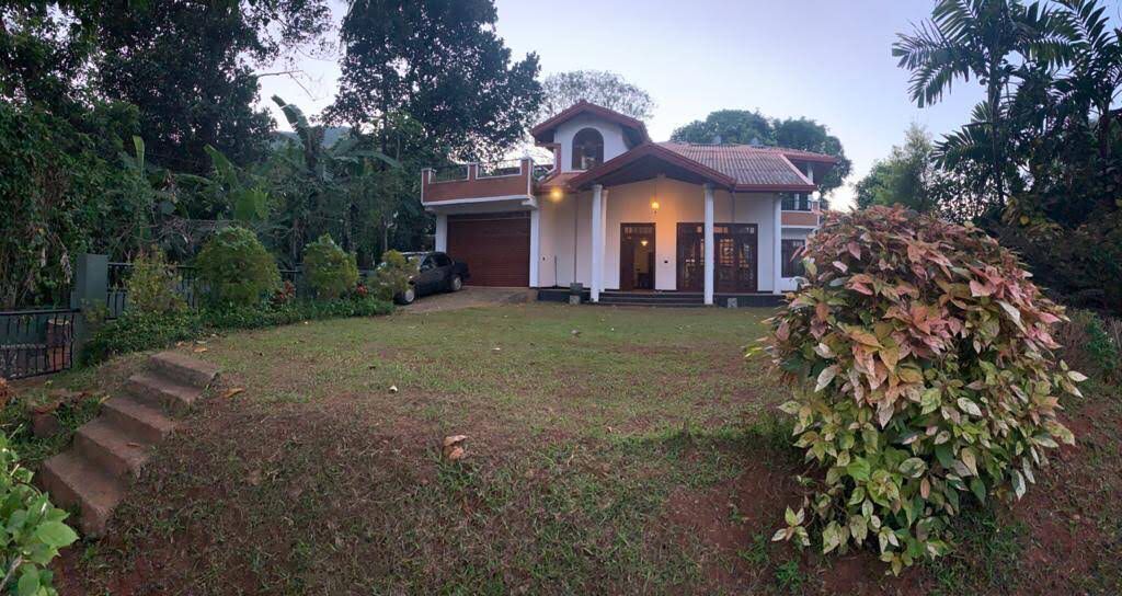 A two-story house with a red-tiled roof, a front porch, and a well-maintained lawn.