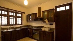 A kitchen with dark wooden cabinets, a built-in oven, and a gas stove. - Kings Court Residency  (Ampiyiya)