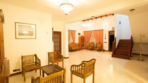 A spacious living area with wooden furniture, a chandelier, and a staircase leading to another level. - Kings Court Residency  (Ampiyiya)