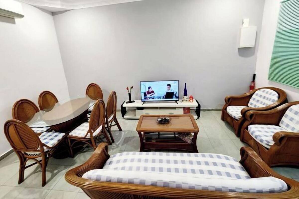 Una sala de estar con una mesa de comedor, sillas, un sofá, una mesita de centro y un televisor.