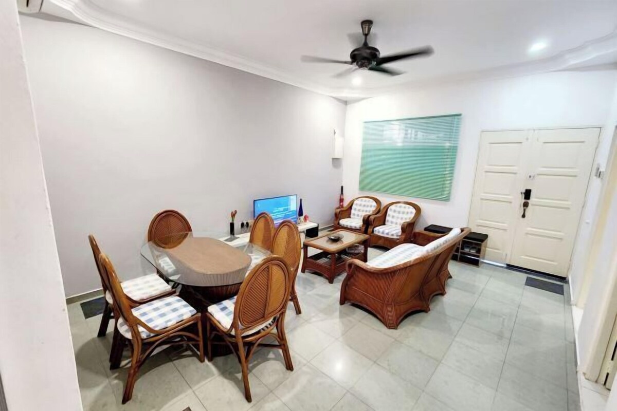 Un área de comedor con una mesa redonda y sillas, un sofá, un ventilador de techo y un televisor montado en la pared.