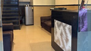 A modern hotel lobby with a staircase, a refrigerator, a sofa, and a reception desk. - Hotel Ajwa (Mumbai)