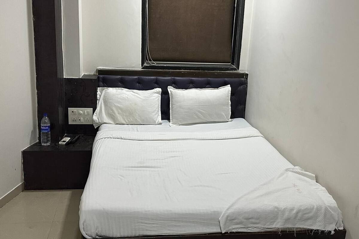 A neatly made bed with white linens, a dark headboard, and a window above.