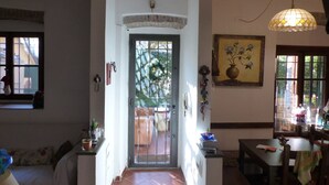 Un pasillo con suelo de baldosas, una puerta que da al exterior y una zona de comedor con mesa y sillas.