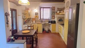 Una cocina con una mesa de comedor, armarios amarillos, un refrigerador y una ventana con rejas.