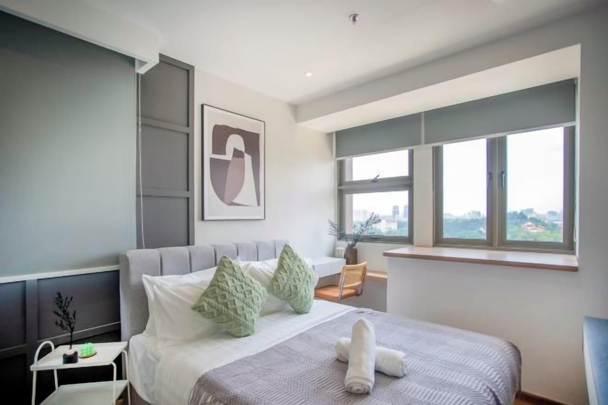 Ein modernes Hotelzimmer mit Bett, Fenster mit Blick auf die Stadt, einem kleinen Tisch und einem Wandbild.